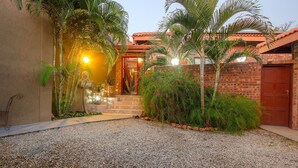 Un edificio de fachada de ladrillo, puerta roja y camino de entrada de grava.