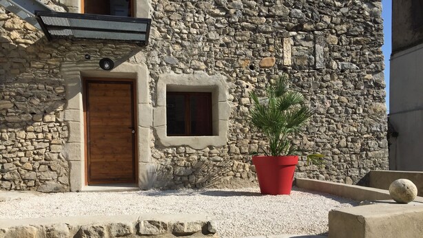 Un bâtiment en pierre avec une porte en bois et une petite fenêtre.