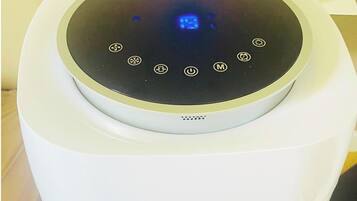 A white air purifier with a circular control panel and a vent at the bottom.
