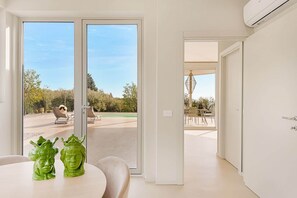 Um interior moderno com área de jantar, vista para uma piscina e porta que dá para um pátio externo.