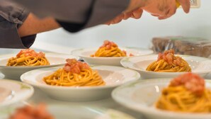 Una persona sirve pasta con camarones en platos.