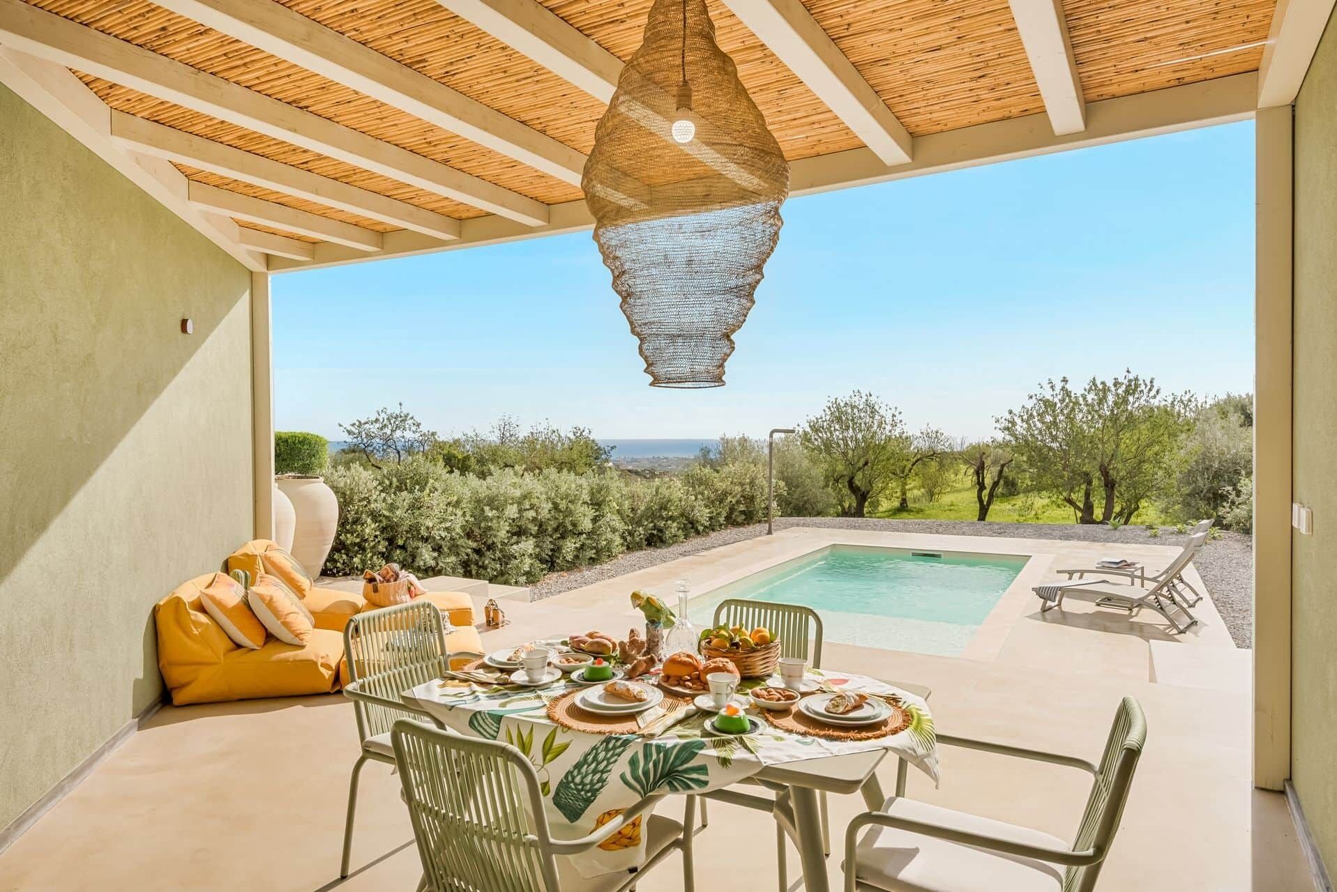 A dining area with a pool, outdoor seating, and a view of the landscape.