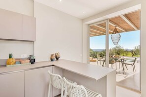 Una cocina moderna con barra, sillas blancas y vistas al exterior.