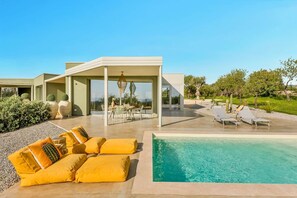 A modern house with a covered patio, outdoor seating, and a swimming pool. - Fior di Noto, Golden Luxe Sicily (Noto)