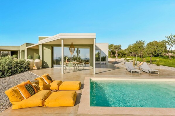 Uma casa moderna com varanda coberta, área de estar externa e piscina.