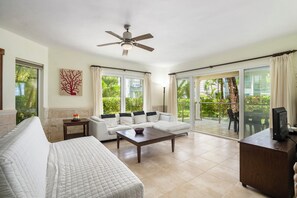 A spacious living room with a sofa, a coffee table, and a TV on a wooden cabinet. - Spacious Condo · Oceanfront Infinity Pool · Minutes from Sosua Center (Sosúa)