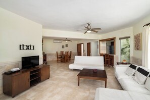 A living room with a TV, sofa, coffee table, and ceiling fan. - Spacious Condo · Oceanfront Infinity Pool · Minutes from Sosua Center (Sosúa)