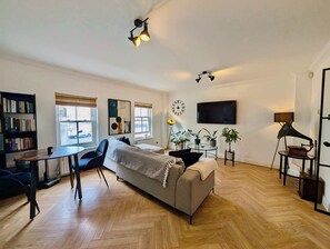 Ein modernes Wohnzimmer mit einer Couch, einem Esstisch, einem Bücherregal und einem Flachbildfernseher.