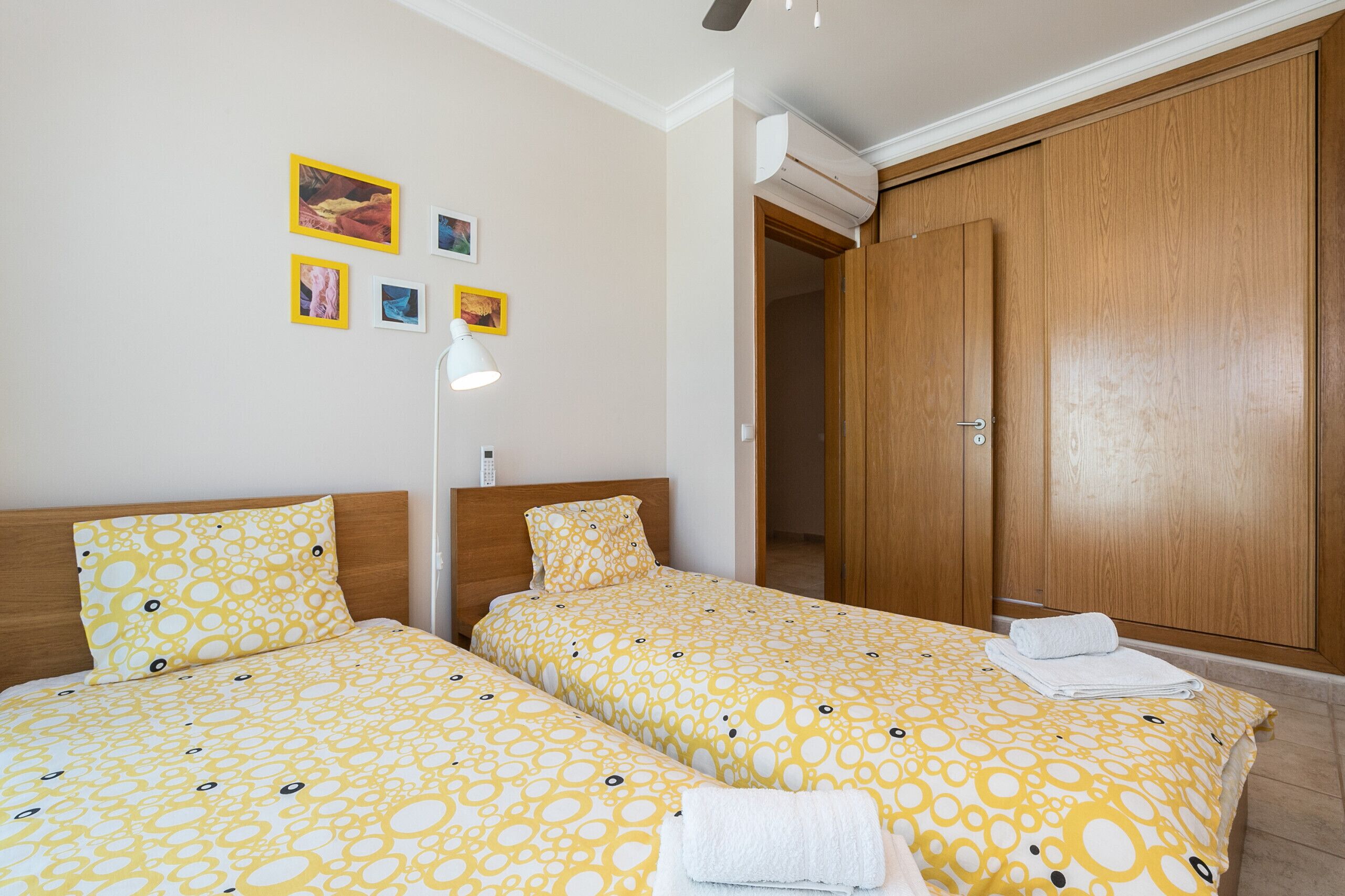 Une chambre avec deux lits, une armoire et un climatiseur fixé au mur.