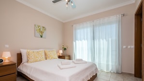 A bedroom with a bed, nightstands, a ceiling fan, a window with curtains, and a wall-mounted picture. - Moradia V3 a 100m da praia by ALGARVEMANTA (24V3) (Manta Rota)