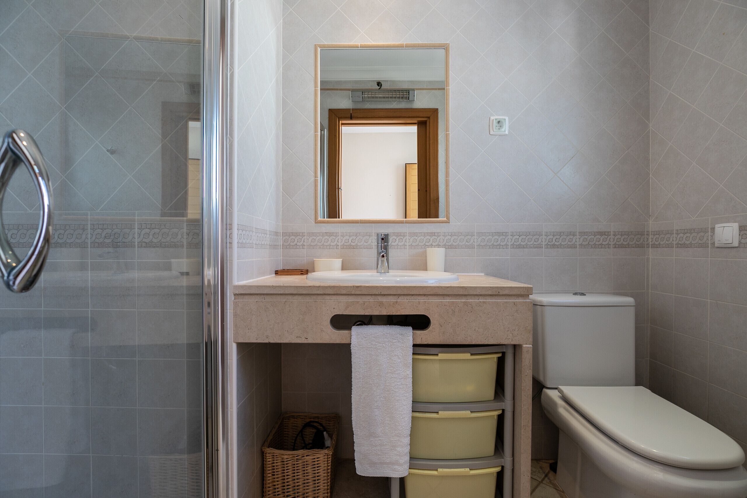 Une salle de bain avec une douche à parois de verre, un lavabo avec un miroir au-dessus et des toilettes.