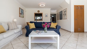 A living room with a sofa, a coffee table, and a vase of flowers. - Moradia V3 a 100m da praia by ALGARVEMANTA (24V3) (Manta Rota)