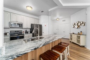 A modern kitchen with white cabinetry, a marble countertop, a stainless steel sink, and a built-in oven. - Vista Cay 3BR near Universal & Convention (Orlando)