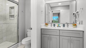 Un bagno moderno con box doccia in vetro, un water e un mobile lavabo con specchio e asciugacapelli.