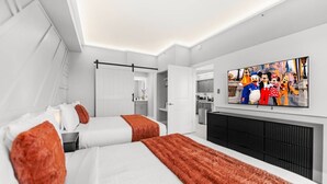 Camera d'albergo moderna con due letti, una TV a schermo piatto e angolo cottura.