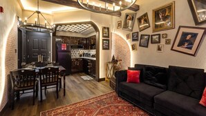 Un salon chaleureux avec un canapé foncé, une table à manger et une cuisine en arrière-plan.