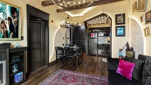 Un salon moderne comprenant un coin repas, une cheminée et une cuisine visible à travers une arche.