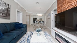A modern living room with a sofa, coffee table, TV, and a dining area with chairs and a table. - Vista Cay Home Near Universal, Pool & Lake (Orlando)