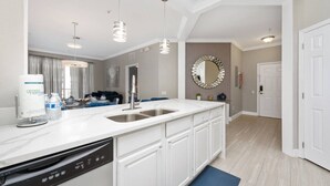 A modern kitchen with a dishwasher, a sink, pendant lights, and a large mirror. - Vista Cay Home Near Universal, Pool & Lake (Orlando)
