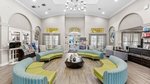 A spacious lobby with a central coffee table, seating area with sofas, a reception desk, and a large chandelier. - Vista Cay Home Near Universal, Pool & Lake (Orlando)
