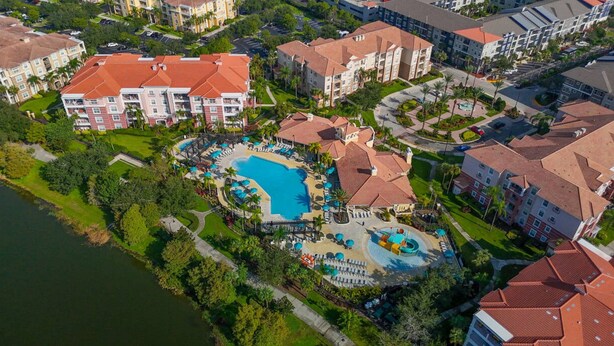 An aerial view of a resort with multiple buildings, a central swimming pool, and surrounding greenery. - Vista Cay Home Near Universal, Pool & Lake (Orlando)