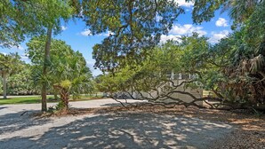 A paved pathway, trees, and a building in the background. - Extensive Outdoor Living, Club Cards Available, Golf Cart Included - 507 Remora Circle (Fripp Island)