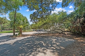 A paved pathway, trees, and a building in the background. - Extensive Outdoor Living, Club Cards Available, Golf Cart Included - 507 Remora Circle (Fripp Island)