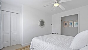 A bedroom with a bed, a ceiling fan, a mirror, and framed pictures on the wall. - Extensive Outdoor Living, Club Cards Available, Golf Cart Included - 507 Remora Circle (Fripp Island)