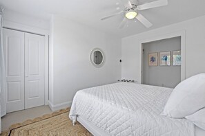 A bedroom with a bed, a ceiling fan, a mirror, and framed pictures on the wall. - Extensive Outdoor Living, Club Cards Available, Golf Cart Included - 507 Remora Circle (Fripp Island)
