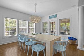 Un espace repas comprenant une longue table, six chaises et un lustre.