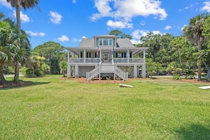 A two-story house with a front porch, a small staircase, and a well-maintained lawn. - Extensive Outdoor Living, Club Cards Available, Golf Cart Included - 507 Remora Circle (Fripp Island)