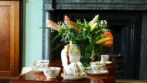 A table with floral arrangements and tea service set.