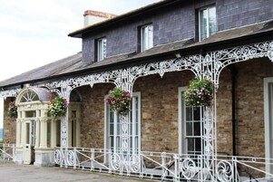 Un edificio con fachada de ladrillo, barandillas metálicas decorativas blancas y cestas de flores.