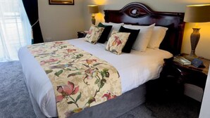 A hotel room with a bed, two bedside lamps, a nightstand, a framed picture on the wall, and a window with curtains.