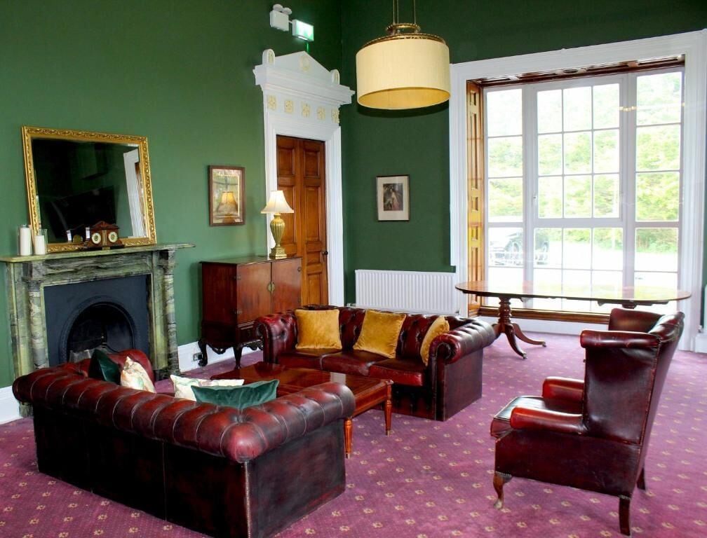 A room with a fireplace, a sofa, a chair, and a large window.