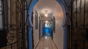 A hallway with a patterned floor, decorative metal railings, and a light fixture.