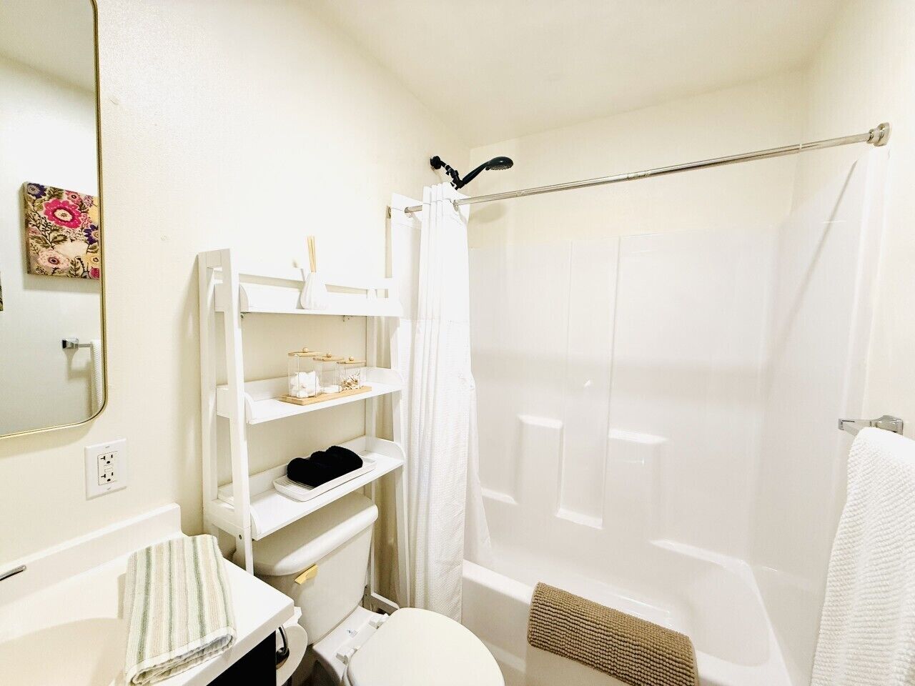 A bathroom with a toilet, a sink, a shower, and a mirror.