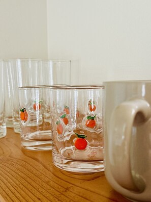 Une rangée de verres transparents ornés de motifs représentant des fruits rouges, posés sur une surface en bois.