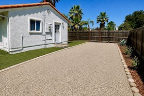 A house with a gravel driveway, a wooden fence, and a lawn.