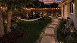Ein Garten mit Hängematte, Gartenmöbeln, einem Kiesweg und Lichterketten.