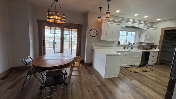 A kitchen with white cabinets, a wooden dining table, and a hanging light fixture.