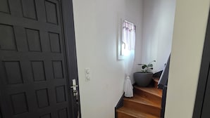 A staircase leading to a second floor, a dark door, and a window with curtains. - Lake View, Spacious House with Garden (Châtellerault)