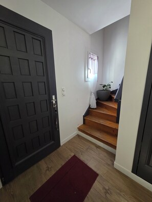 A staircase leading to a second floor, a dark door, and a window with curtains. - Lake View, Spacious House with Garden (Châtellerault)