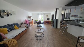 A modern living room with a sofa, a dining area, and a kitchen. - Lake View, Spacious House with Garden (Châtellerault)