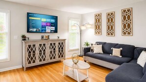 Un soggiorno con TV, mobiletto in legno, divano e pannelli decorativi a parete.