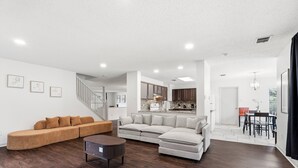 Una sala moderna con un sofá modular, una mesa de centro y un comedor con mesa y sillas.