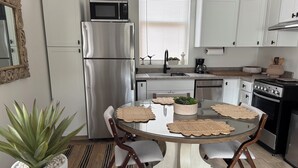 Eine moderne Küche mit einem Edelstahlkühlschrank, einer Mikrowelle, einem Herd und einem Esstisch mit Platzsets.