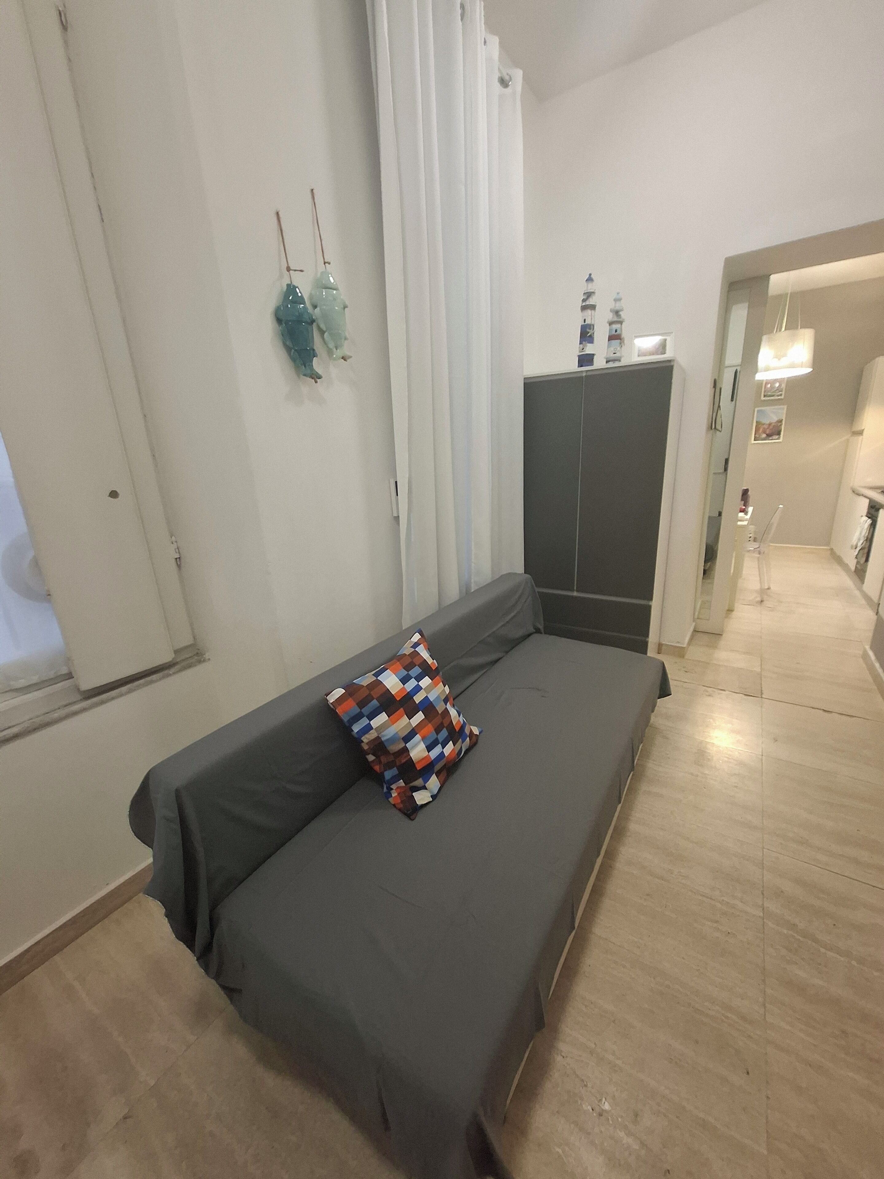Un dormitorio con cama, armario, ventana con cortinas y un pasillo que conduce a un baño.