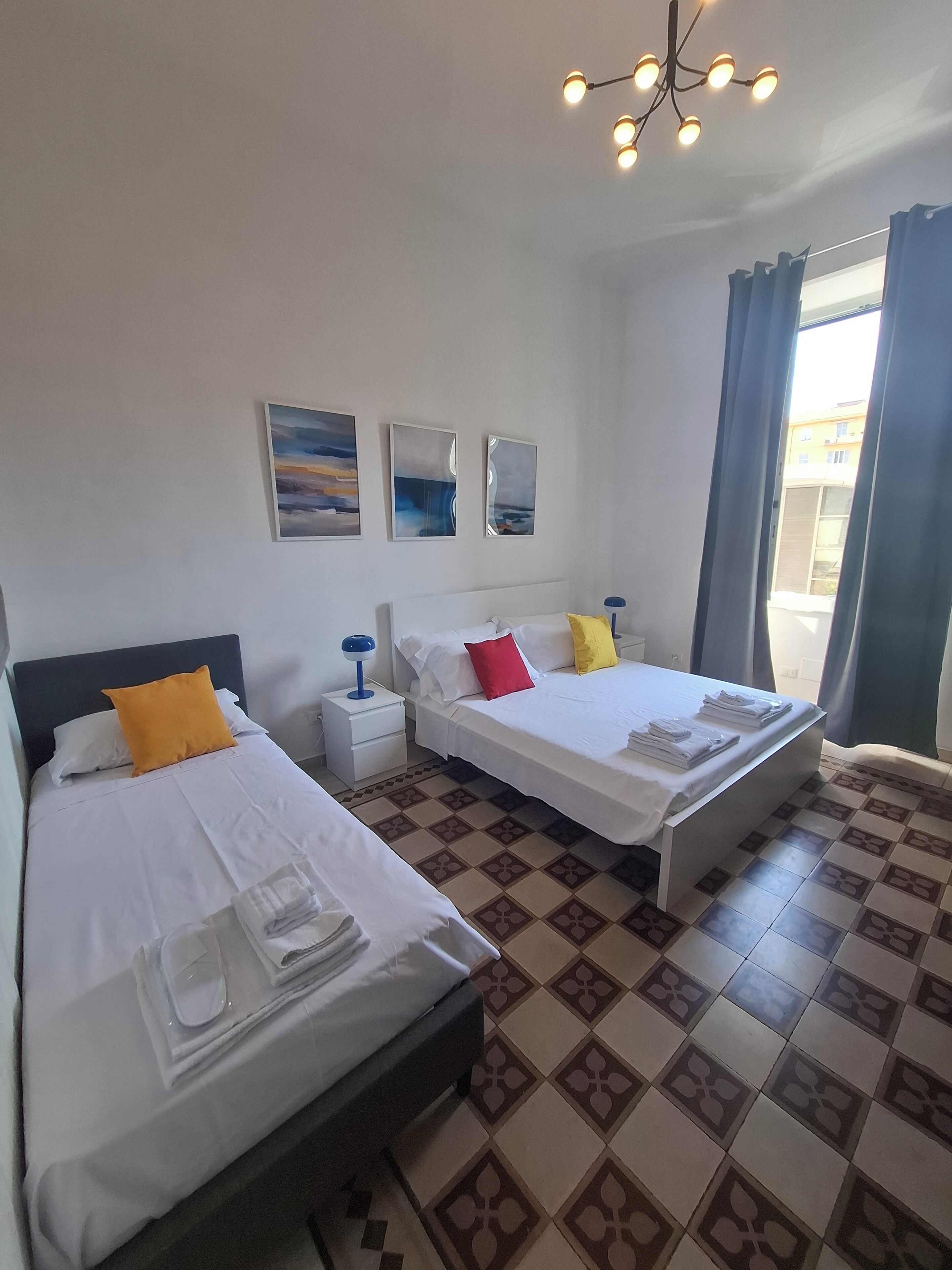 Ein Hotelzimmer mit zwei Betten, einem Nachttisch, einer Lampe und Bildern an der Wand.