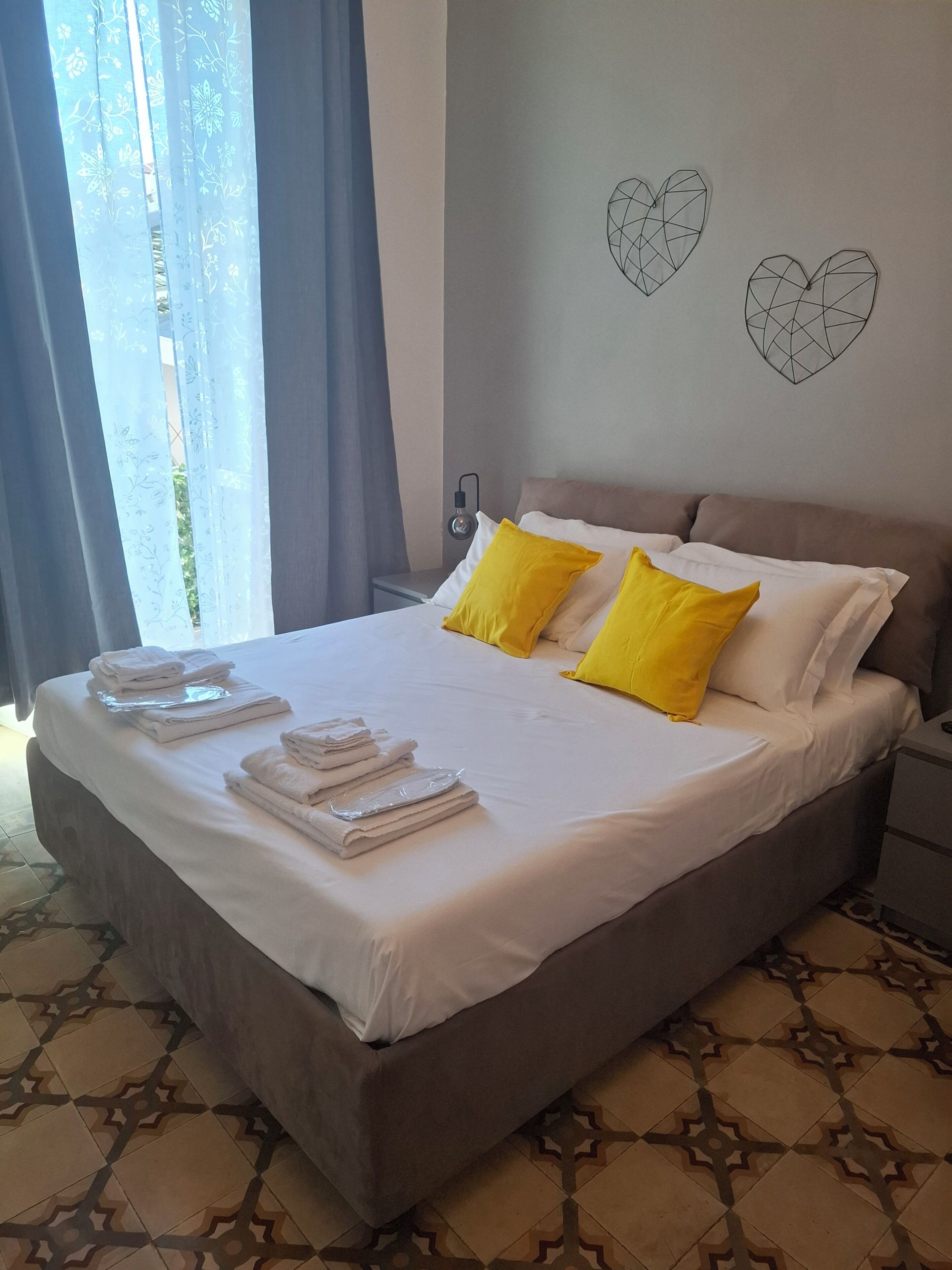 Una cama bien hecha con toallas, una lámpara de noche y decoración en la pared.
